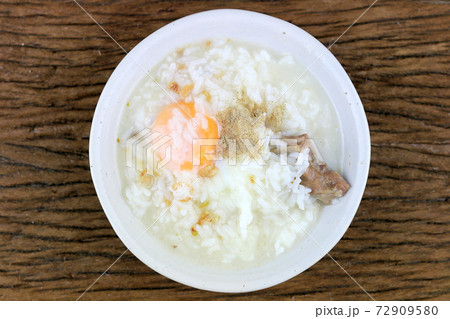 Homemade Thai Rice Soup With chicken, pork and Soft boiled egg or onsen egg in white blow on rustic wooden background. Thai style Food. Top view. 72909580