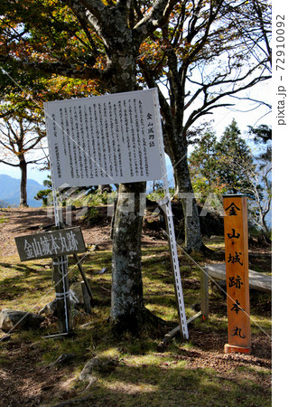 丹波市にある金山城跡の頂上の金山城跡本丸、金山城本丸跡を示す頂上標と金山城物語の説明看板 縦位置 丹波市にある金山城跡の頂上の金山城跡本丸、金山城本丸跡を示す頂上標と金山城物語の説明看板 縦位置 72910092