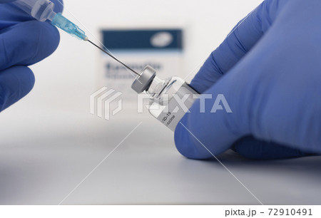 Close up human fingers in gloves, holding syringe with needle and covid-19 vaccine vial. Medical concept. Close up human fingers in gloves, holding syringe with needle and covid-19 vaccine vial. Medical concept. 72910491