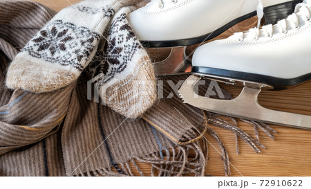 Winter flatlay with white skates for figure skating, a warm scarf and mittens Winter flatlay with white skates for figure skating, a warm scarf and mittens 72910622
