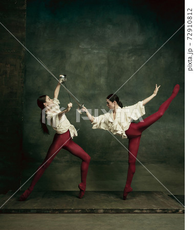 Two young female ballet dancers like duelists with swords. Ballet and contemporary choreography concept. Creative art photo. Two young female ballet dancers like duelists with swords. Ballet and contemporary choreography concept. Creative art photo. 72910812