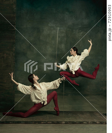 Two young female ballet dancers like duelists with swords. Ballet and contemporary choreography concept. Creative art photo. Two young female ballet dancers like duelists with swords. Ballet and contemporary choreography concept. Creative art photo. 72910903