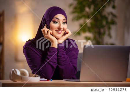 Happy muslim woman at home during online lesson. Modern technologies, remote education, ethnicity concept Happy muslim woman at home during online lesson. Modern technologies, remote education, ethnicity concept 72911273