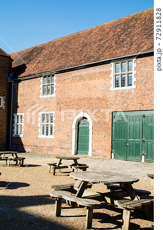 歴史的な赤煉瓦づくりの建物と木製の丸テーブル イギリス郊外のオスタリーパークにて 歴史的な赤煉瓦づくりの建物と木製の丸テーブル イギリス郊外のオスタリーパークにて 72911828