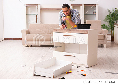 Young male carpenter repairing furniture at home Young male carpenter repairing furniture at home 72913688
