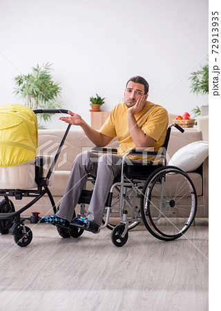Young man contractor in wheel-chair looking after newborn 72913935