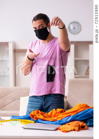 Young male tailor sewing masks at home during pandemic 72913990