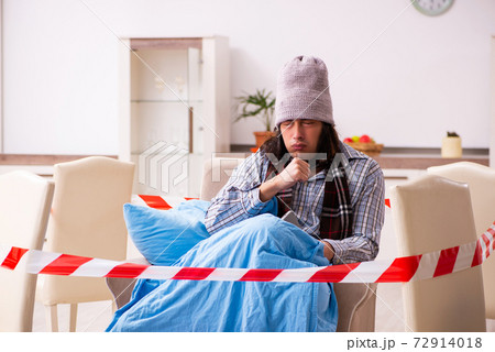Young sick man suffering at home in pandemic concept 72914018