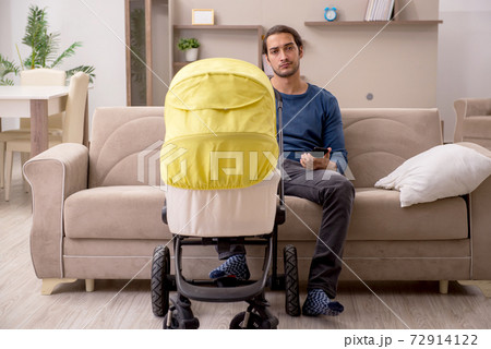 Young male contractor looking after baby at home 72914122