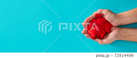Woman hands holding red hearts on blue background Woman hands holding red hearts on blue background 72914406