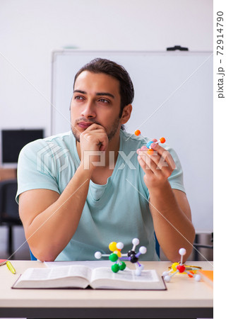 Young male student physicist studying molecular model at home Young male student physicist studying molecular model at home 72914790
