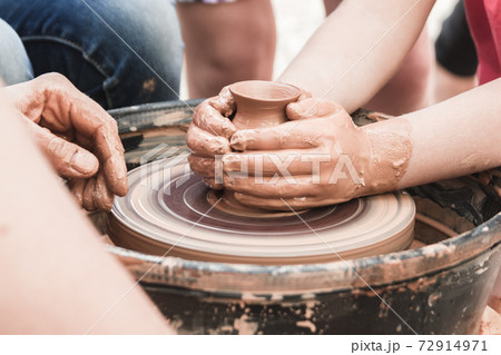A close up view on ceramic production process on potter's wheel with children. Clay crafts with kids concept 72914971