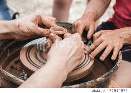 A close up view on ceramic production process on potter's wheel with children. Clay crafts with kids concept 72914972