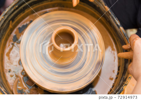 A close up view on ceramic production process on potter's wheel with children. Clay crafts with kids concept 72914973