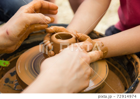 A close up view on ceramic production process on potter's wheel with children. Clay crafts with kids concept 72914974