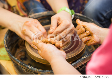 A close up view on ceramic production process on potter's wheel with children. Clay crafts with kids concept A close up view on ceramic production process on potter's wheel with children. Clay crafts with kids concept 72914979