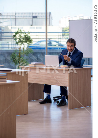 Young male teacher in suit in the classroom 72915375