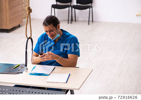 Young male doctor committing suicide at workplace Young male doctor committing suicide at workplace 72916626
