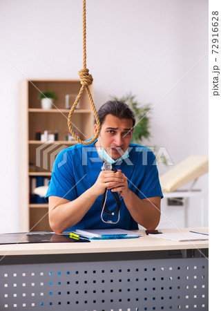 Young male doctor committing suicide at workplace Young male doctor committing suicide at workplace 72916628