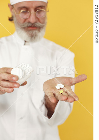 Old doctor standing in a white uniform 72918812