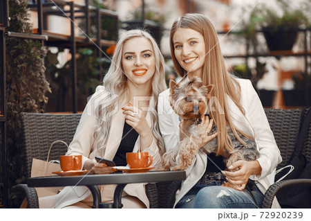 Elegant women sitting in a summer cafe 72920239