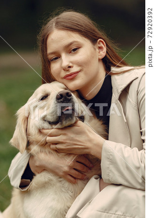 Woman walks in autumn forest with a dog 72920392