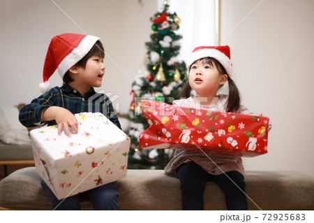 クリスマスプレゼントを開ける子供たちの写真素材