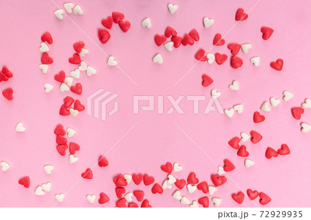 Sugar heart shaped sprinkles on pastel pink background Sugar heart shaped sprinkles on pastel pink background 72929935