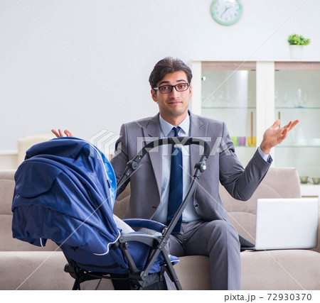 Businessman looking after newborn baby at home and teleworking Businessman looking after newborn baby at home and teleworking 72930370