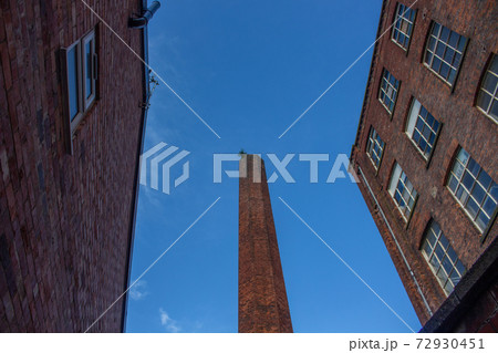 View of traditional Northern British 1880s mill buildings and chimney, looking upwards against blue sky. Stockport, Cheshire, UK. View of traditional Northern British 1880s mill buildings and chimney, looking upwards against blue sky. Stockport, Cheshire, UK. 72930451
