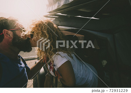Adult couple in love kiss outside the car and travel together - concept of free and happy lifestyle for beautiful people traveling and enjoying life Adult couple in love kiss outside the car and travel together - concept of free and happy lifestyle for beautiful people traveling and enjoying life 72931229