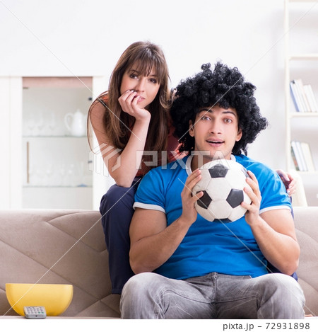 Young man watching football with his wife at home Young man watching football with his wife at home 72931898