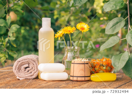Towel, soap with marigold extract, calendula flowers in a flask with natural background. Towel, soap with marigold extract, calendula flowers in a flask with natural background. 72932494
