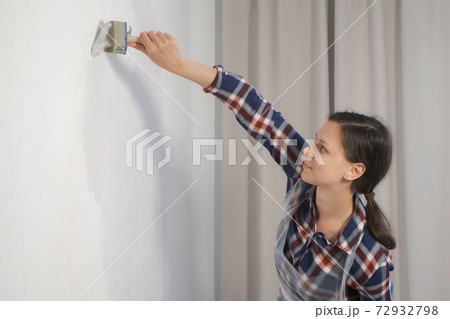 Woman house painter is painting wall using brush doing renovation at home. Woman house painter is painting wall using brush doing renovation at home. 72932798