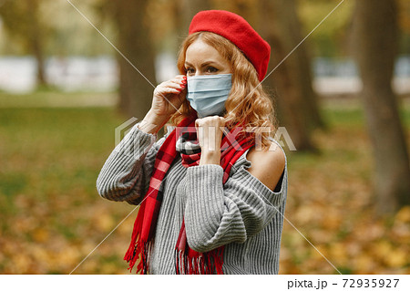 Woman in a mask stands in a park 72935927