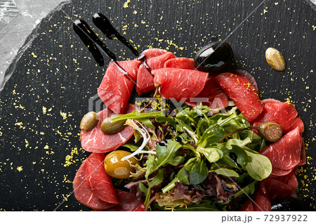 Beef carpaccio with arugula on a black plate, traditional Italian cuisine. Dark key, copy space, Beef carpaccio with arugula on a black plate, traditional Italian cuisine. Dark key, copy space, 72937922
