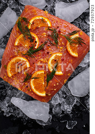 salmon fillet with orange slices on pieces of ice on a black background salmon fillet with orange slices on pieces of ice on a black background 72937923