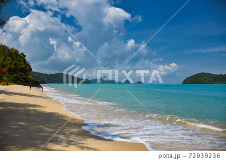 Waves of the azure Andaman sea under the blue sky reaching the shores of the sandy beautiful exotic and stunning Cenang beach in Langkawi island 72939236
