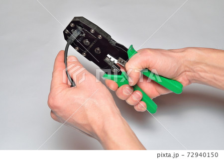 Hands of the installer of computer networks crimped connector on the cable Hands of the installer of computer networks crimped connector on the cable 72940150