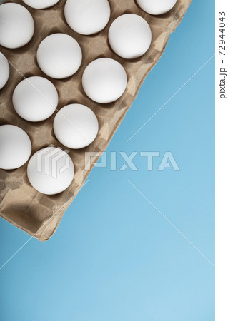 Container of white eggs on blue background Container of white eggs on blue background 72944043