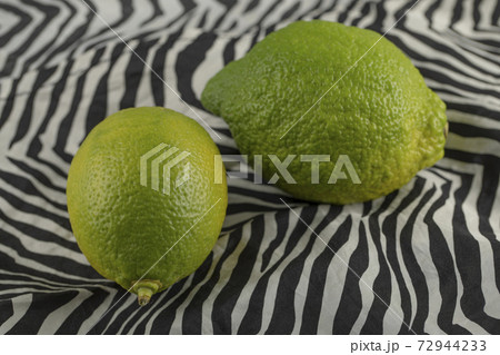 Green lemons on a beautiful tablecloth 72944233