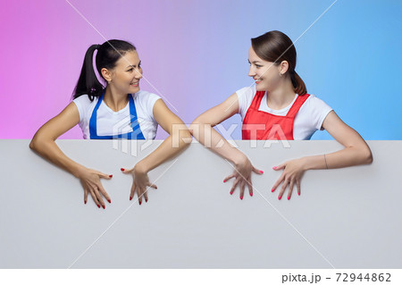 two girls in aprons pose with a white Billboard. advertising concept two girls in aprons pose with a white Billboard. advertising concept 72944862