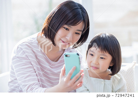 ファミリー スマホを見るママと女の子 ファミリー スマホを見るママと女の子 72947241