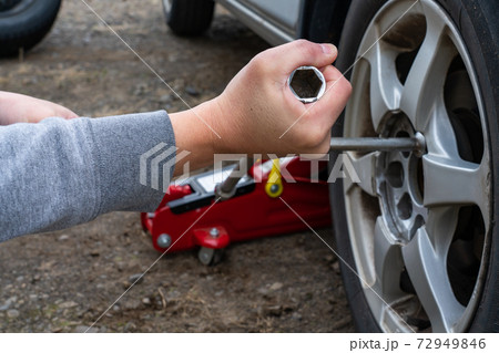 タイヤのナットを十字レンチで締めている男性の手 72949846