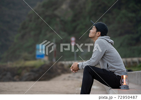 二地域暮らしで週末、早朝に浜辺でリラックスする男性 72950487