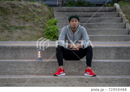 週末田舎域暮らしで、早朝に浜辺でリラックスする男性 72950488