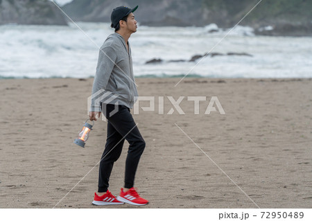 二地域暮らしで週末、早朝に海を散歩して満喫する男性 72950489