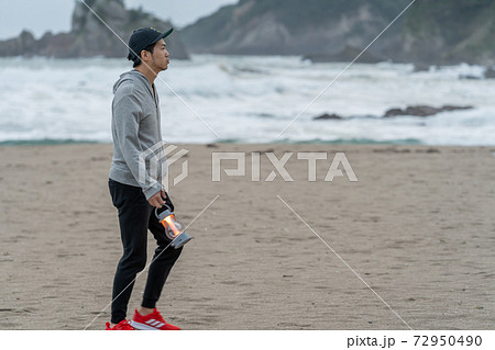 地方移住をして、早朝に海を散歩して満喫する男性 72950490
