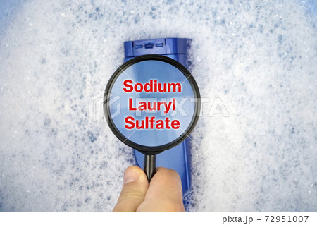 Chemical components on the shampoo label: Sodium Lauryl Sulfate (sls, sles). A hand holds a blue jar and a magnifier, where the harmful ingredients of a detergent are written in close up. Chemical components on the shampoo label: Sodium Lauryl Sulfate (sls, sles). A hand holds a blue jar and a magnifier, where the harmful ingredients of a detergent are written in close up. 72951007