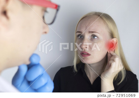 A woman suffers from pain in the ear. The auditory meatus hurts due to otitis media, cerumen plug, ear boil, or trigeminal neuralgia. On examination by a doctor. A woman suffers from pain in the ear. The auditory meatus hurts due to otitis media, cerumen plug, ear boil, or trigeminal neuralgia. On examination by a doctor. 72951069